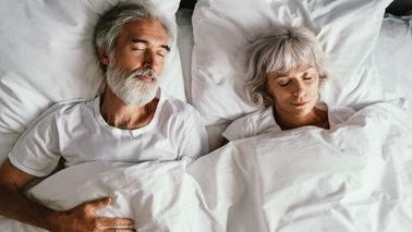 Älteres Paar liegt schlafend im Bett