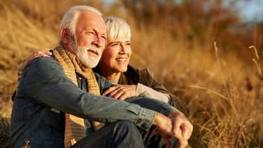 Älteres Paar im warmen Sonnenlicht in der Natur – Thema Haut im Alter