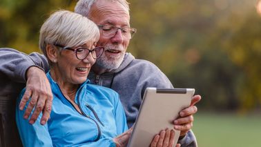 Seniorenpaar mit Tablet im Park – informiert sich über Herzgesundheit im Alter