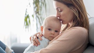 Mutter hält Baby mit Erkältung in ihren Armen.