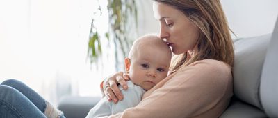 Mutter hält Baby mit Erkältung in ihren Armen.