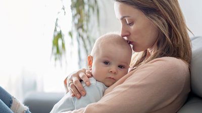 Mutter hält Baby mit Erkältung in ihren Armen.