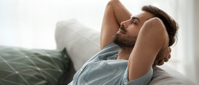 Ein Mann lehnt sich entspannt auf dem Sofa zurück - Symbol für Resilienz