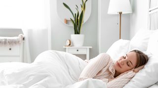 Frau schläft entspannt in einem hellen Schlafzimmer