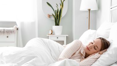 Frau schläft entspannt in einem hellen Schlafzimmer