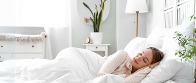 Frau schläft entspannt in einem hellen Schlafzimmer