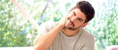 Mann fasst sich an den Nacken – typische Nackenschmerzen morgens durch Verspannungen