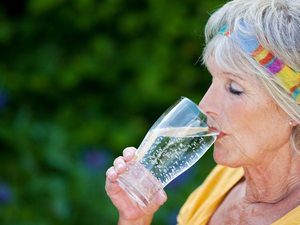 Ältere Frau beim Trinken von Wasser zur Unterstützung der Nierenfunktion im Alter