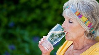 Ältere Frau beim Trinken von Wasser zur Unterstützung der Nierenfunktion im Alter