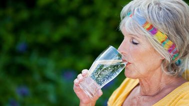 Ältere Frau beim Trinken von Wasser zur Unterstützung der Nierenfunktion im Alter