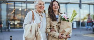 Zwei Frauen lachen und tragen Einkaufstaschen beim gemeinsamen Stadtbummel.