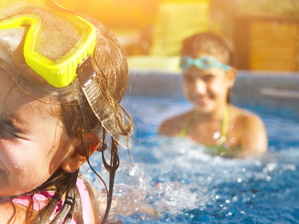 Mädchen mit Taucherbrille spielen im Schwimmbecken