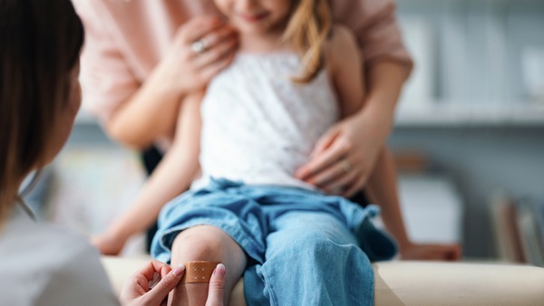 Ein kleines Mädchen bekommt ein Pflaster und wird von Ihrer Mutter getröstet