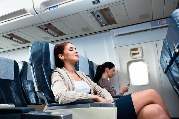 Frau sitzt ganz entspannt im Flugzeug und hört Musik