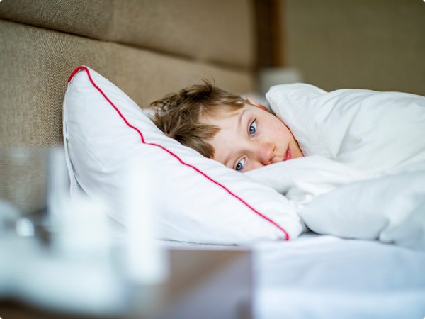 Kleiner Junge liegt krank im Bett