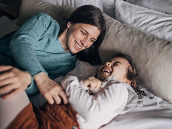 Mutter und Tochter liegen im Bett und lachen