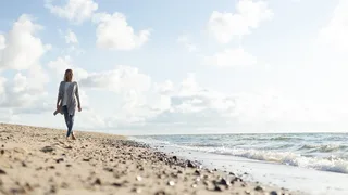 Eine Frau läuft im Sand am Strand entlang