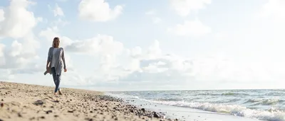 Eine Frau läuft im Sand am Strand entlang