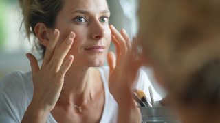 Frau cremt sich im Gesicht ein