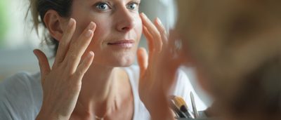 Frau cremt sich im Gesicht ein