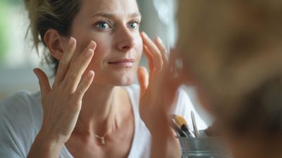 Frau cremt sich im Gesicht ein