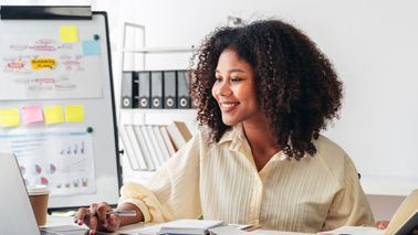 Frau sitzt am Schreibtisch und arbeitet.