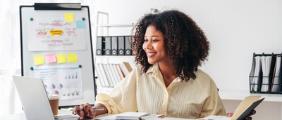 Frau sitzt am Schreibtisch und arbeitet.