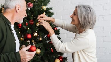 Älteres Paar schmückt ohne Weihnachtstress seinen Weihnachtsbaum