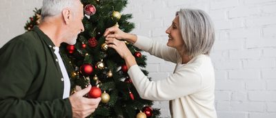 Älteres Paar schmückt ohne Weihnachtstress seinen Weihnachtsbaum