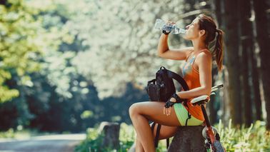 Frau mit Mountainbike macht Wasserpause.