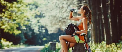 Frau mit Mountainbike macht Wasserpause.