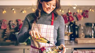Lächelnde Frau steht in der Küche und macht einen Salat