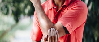 Mann mit Tennisarm oder Golferarm legt Hand auf schmerzenden Ellenbogen.