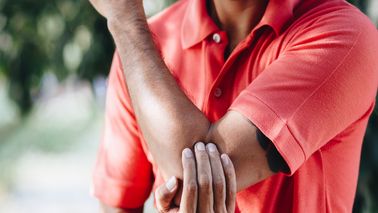 Mann mit Tennisarm oder Golferarm legt Hand auf schmerzenden Ellenbogen.