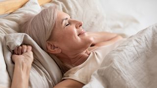 Ältere Frau liegt entspannt und erleichtert in Ihrem Bett