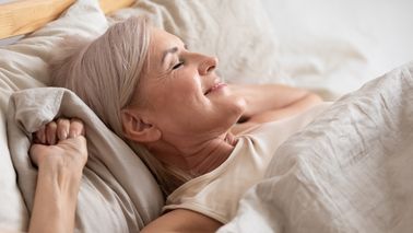 Ältere Frau liegt entspannt und erleichtert in Ihrem Bett