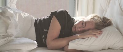 Frau schläft bei Hitze in einem Bett.