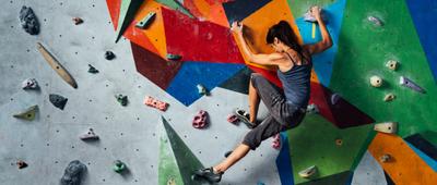 Frau beim Bouldern an einer Kletterwand.