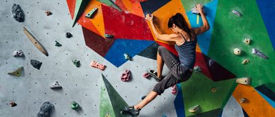Frau beim Bouldern an einer Kletterwand.