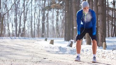 Läufer macht im verschneiten Wald eine Verschnaufpause