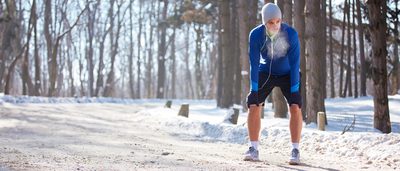 Läufer macht im verschneiten Wald eine Verschnaufpause