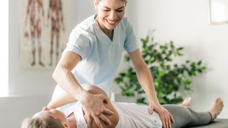 Physiotherapeutin behandelt Frau auf einer Liege.