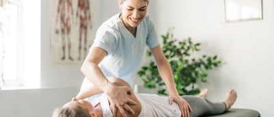 Physiotherapeutin behandelt Frau auf einer Liege.