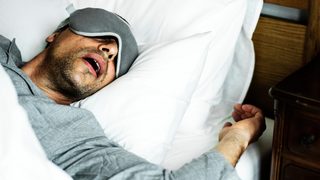 Mann schläft und schnarcht mit offenem Mund