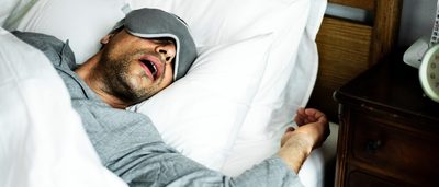 Mann schläft und schnarcht mit offenem Mund