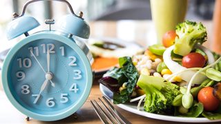 Teller mit Essen und eine Uhr als Symbol für Intervallfasten.