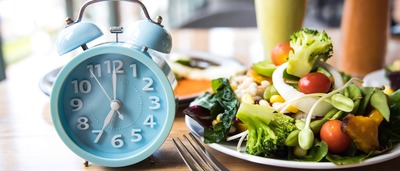 Teller mit Essen und eine Uhr als Symbol für Intervallfasten.