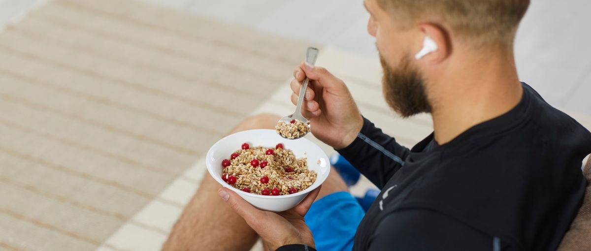 Mann in Sport-Dress isst eine Schüssel Müsli mit Früchten