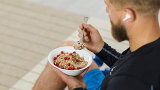 Mann in Sport-Dress isst eine Schüssel Müsli mit Früchten