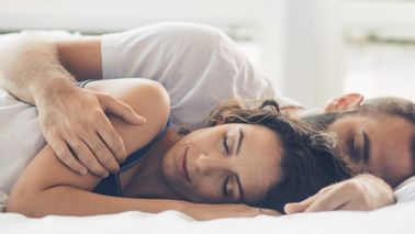Paar liegt entspannt im Bett und schläft